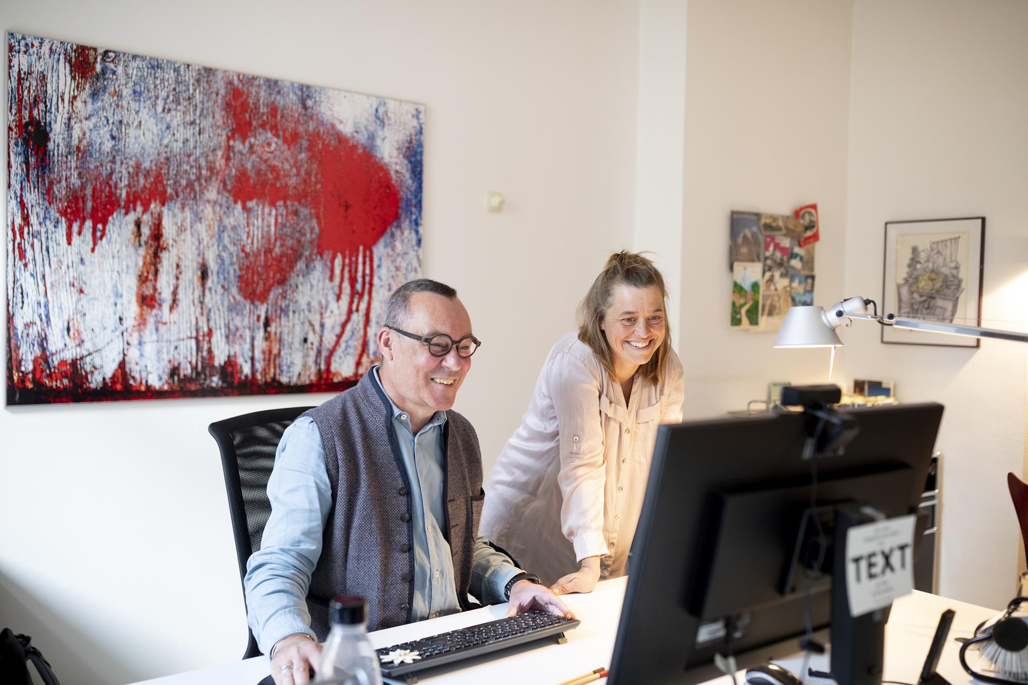 Franziska Kučera und Frank Martin Siefarth, schauen in einen PC-Bildschirm. Sie sind das Team der WORTSTATT, dem Medienbüro für Konzeption, Textgestaltung, Redaktion, Lektorat.