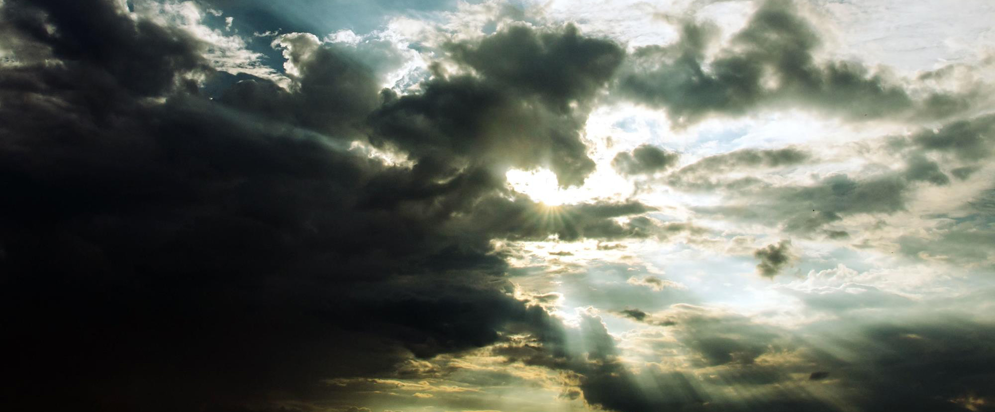 Sturmwolke, die links im Bild sehr dunkel und geschlossen ist. Rechts bricht die Sonnen mit ihren Strahlen hindurch.